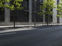 the road is empty near some buildings and trees that are lined with metal barriers on both sides