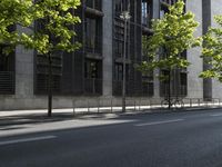 the road is empty near some buildings and trees that are lined with metal barriers on both sides