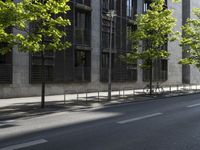 the road is empty near some buildings and trees that are lined with metal barriers on both sides