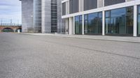 a woman is on a skateboard and it is empty in the street outside of an office building