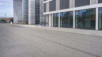 a woman is on a skateboard and it is empty in the street outside of an office building