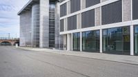 a woman is on a skateboard and it is empty in the street outside of an office building