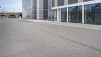 a woman is on a skateboard and it is empty in the street outside of an office building