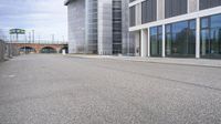 a woman is on a skateboard and it is empty in the street outside of an office building