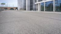 a woman is on a skateboard and it is empty in the street outside of an office building