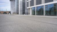 a woman is on a skateboard and it is empty in the street outside of an office building