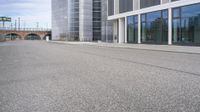 a woman is on a skateboard and it is empty in the street outside of an office building