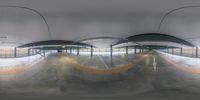 there is a fish eye lens image showing an empty underground tunnel with ramps and concrete floors