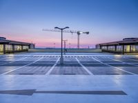 an empty parking lot in a park with a large crane in the distance at dusk