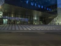 a person walking in front of the fluturium by night with a traffic light
