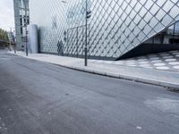 a street with two buildings in the background that are clad in glass and metal, next to street lights