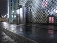 a street and some very tall buildings at night - colored lights in the dark and wet wet surface