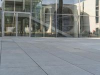 a man wearing a suit walking outside a glass building with steps, and stairs,