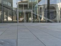 a man wearing a suit walking outside a glass building with steps, and stairs,