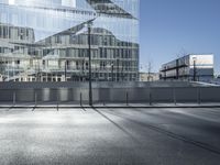 a large glass building sitting in the middle of a street next to a park and road