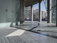 a wide walkway with metal grates going through it and a sky background looking over a city