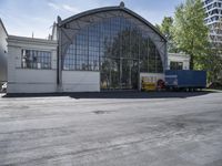 a large glass building in the background and trucks parked at the side of it to the right