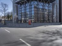 a big modern glass building by a street corner with a red telephone box on the right