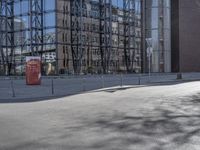 a big modern glass building by a street corner with a red telephone box on the right