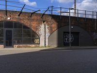 a picture of the side of a building with graffiti on it and a man riding a bike past