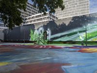 a kid rides a skateboard across a colorful field of paint in front of a building