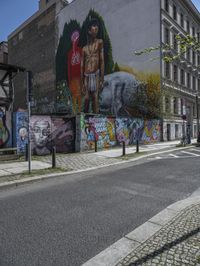 a large, tall, colorful mural in the middle of a town street, on a city block