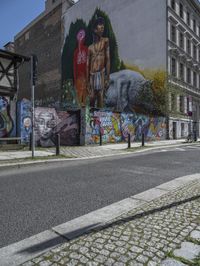 a large, tall, colorful mural in the middle of a town street, on a city block