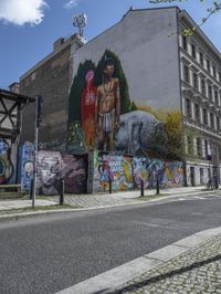 a large, tall, colorful mural in the middle of a town street, on a city block