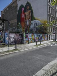 a large, tall, colorful mural in the middle of a town street, on a city block