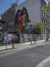 a large, tall, colorful mural in the middle of a town street, on a city block