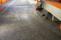 a close up of a brick floor with a red wall in the background and a concrete curb