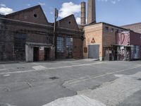 an industrial city street and brick buildings with graffiti painted all over it's walls