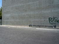 an empty parking lot with graffiti on it's side and benches in front of it