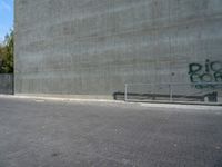 an empty parking lot with graffiti on it's side and benches in front of it