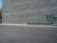 an empty parking lot with graffiti on it's side and benches in front of it