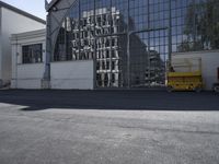 an image of an industrial facility reflecting in the windows of the building next to it