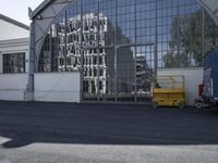 an image of an industrial facility reflecting in the windows of the building next to it