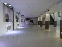 a dimly lit, long hallway leads to the upper floors of an office building with glass railings leading to several rooms