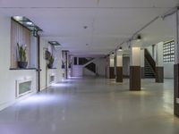 a dimly lit, long hallway leads to the upper floors of an office building with glass railings leading to several rooms