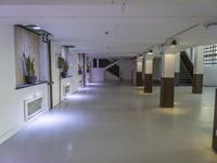 a dimly lit, long hallway leads to the upper floors of an office building with glass railings leading to several rooms