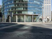 this is the entrance to a modern office building near a street corner, showing the round stone facade