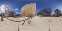 fisheye lens image of a building near a park area with benches and a sculpture