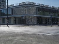 a building on a corner with the front of the store closed off with a woman standing in front of the building