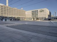 a large building in the background with a train track passing by it in front of a city plaza