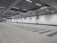 a empty airport terminal with white walls and gray flooring and lights on all sides