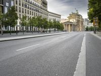 empty street with a view to a building in the distance with streetlights on the sides of the road