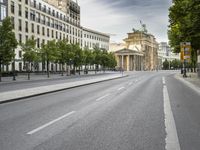 empty street with a view to a building in the distance with streetlights on the sides of the road