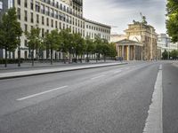 empty street with a view to a building in the distance with streetlights on the sides of the road