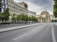 empty street with a view to a building in the distance with streetlights on the sides of the road