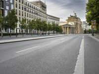 empty street with a view to a building in the distance with streetlights on the sides of the road